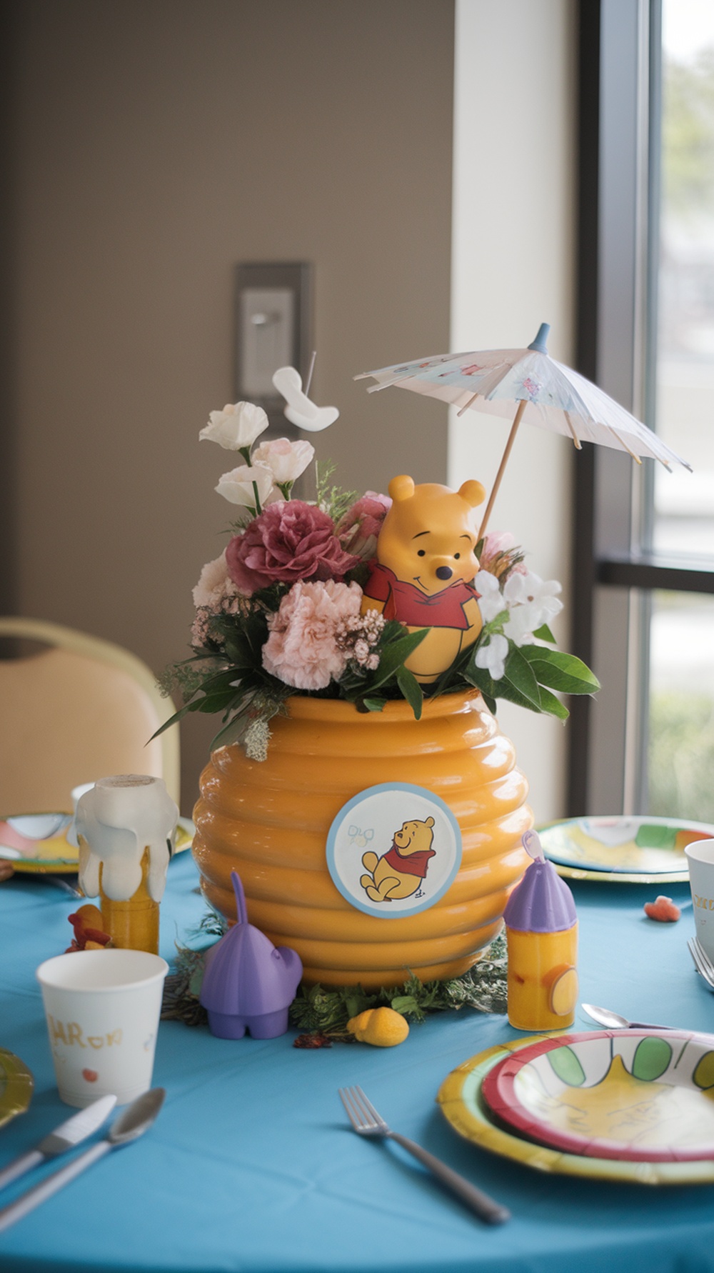 A honey pot centerpiece with flowers and a Winnie the Pooh figure